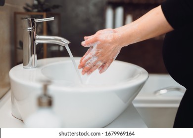 pregnant woman Washing hands with soap under the faucet with water at home in bathroom. - Shutterstock ID 1679969164