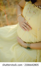 Pregnant woman, wearing light yellow dress, holding in hands  bouquet of daisy flowers ."selective focus" "shallow depth of field" "follow focus" or " blur".