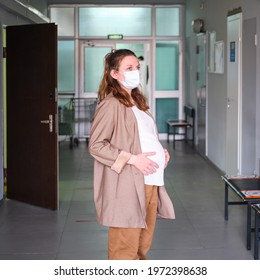 A Pregnant Woman Wearing A Medical Mask On Her Face Stands In The Lobby Of The Hospital