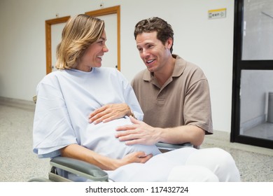 Pregnant woman in wheelchair talking with partner in hospital corridor - Powered by Shutterstock