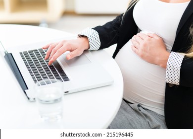 Pregnant woman at work using laptop 
