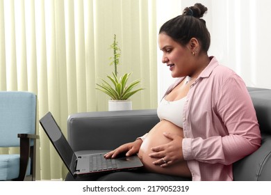 Pregnant Woman Working At Home Sitting On Couch, Side View