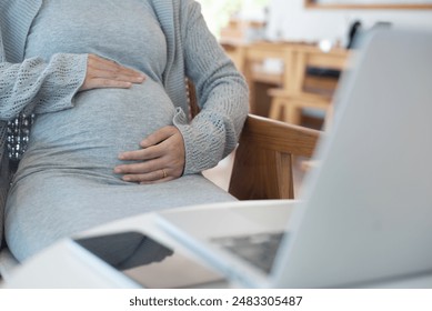 Pregnant woman working on laptop. Cropped image of pregnant businesswoman sitting at table typing on laptop at her working place in office - Powered by Shutterstock