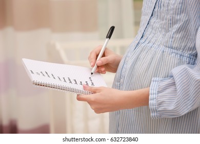 Pregnant Woman Writing Baby Names In Notebook At Home