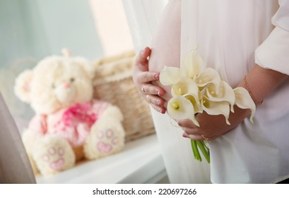 pregnant woman's tummy.
Portrait of pregnant girl with flowers.
9 months of pregnancy  and motherhood close up.
Pregnant woman strokes her tummy.  woman in anticipation of child birth.