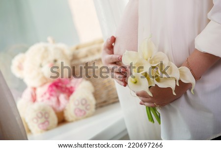 pregnant woman's tummy.
Portrait of pregnant girl with flowers.
9 months of pregnancy  and motherhood close up.
Pregnant woman strokes her tummy.  woman in anticipation of child birth.