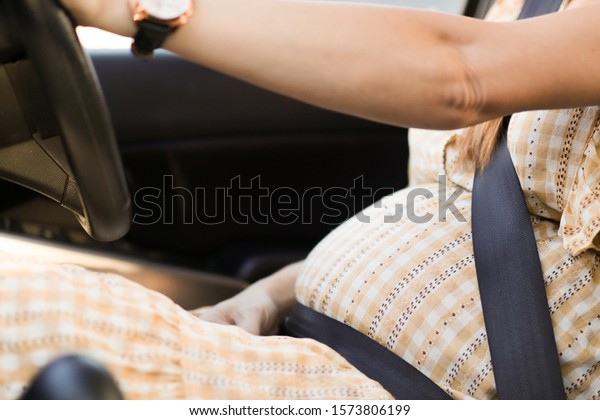 Pregnant women in\
yellow plaid maternity clothes, sitting and girded\
The seat belt\
drives to work in the\
morning