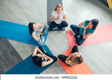 Pregnant women in yoga class sitting on mats stretching arms in a fitness studio