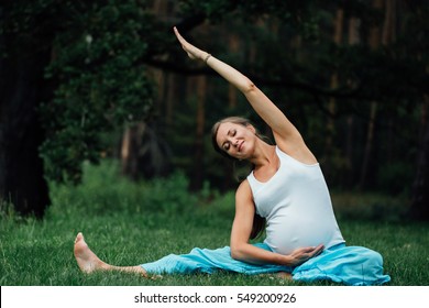 pregnant yoga prenatal maternity doing different exercises. in park on the grass, breathing, stretching, statics. outdoor, forest and river. concept of healthy lifestyle and relaxation. meditation.