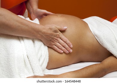 Pregnant Young Latina Woman With Beautiful Skin, Being Wrapped With A Towel, Lying On A Bed And Having A Relaxing Prenatal Massage, Various Techniques