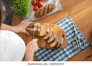 Pregnant young woman cuts bread into slices for sandwiches - Powered by Shutterstock