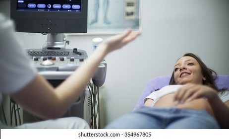 Pregnant Young Woman Having 4D Ultrasound Scan.Teenage Mom Having A Baby.Ultrasound Imaging,examination Of The Abdomen.Doctor Explaining Everything Is Ok.Good Doctor And Patient Communication,Smiling