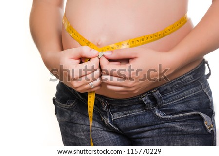 The pregnant young woman measures a stomach by tape