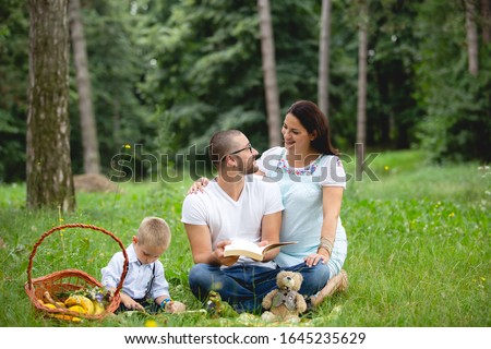 Pregnant young woman sitting with her family in nature
