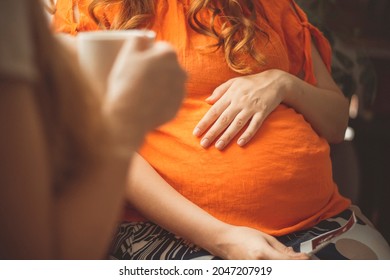 pregnant young woman sitting in kitchen with girlfriend talking about ultrasound snapshot, motherhood concept, pregnancy and friendship