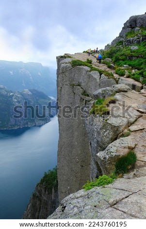 Preikestolen, Norway or Prekestolen or Pulpit Rock is a famous tourist attraction near Stavanger, Norway. Preikestolen is a steep cliff which rises above the Lysefjord. Silhouettes of people on cliff.