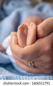 premature newborn baby  with mothers hand  holding tiny feet represented by a reborn doll, background for copy space and text overlay 
