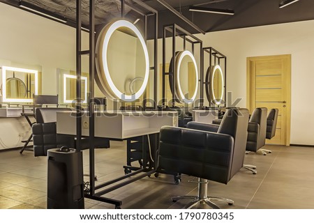 Premium coworking center for hair masters: workplace of the hairdresser with illuminated mirrors and comfortable chairs. Concept of contemporary interior design for hairdresser. Horizontal orientation