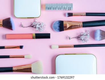 premium makeup brushes, eyeshadow palette, blush and listick on a colored pink background, creative cosmetics flat lay