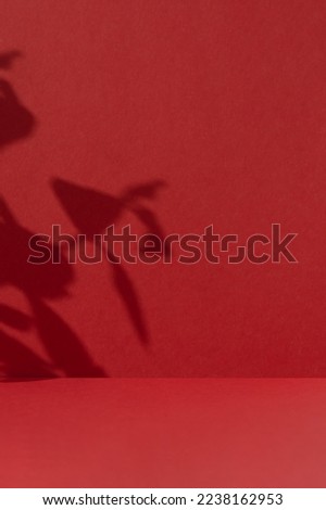 Premium podium with a shadow of plant leaves on a red background. Minimal abstract backdrop for the presentation of a cosmetic product. Showcase, display case.