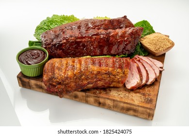 Premium Pork Baby Back Ribs And Whole Pork Tenderloin On A Wood Cutting Board, Isolated On White Background.