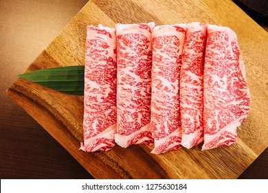 Premium Rare Slices Wagyu A5 beef with high-marbled texture on square wooden plate served for Sukiyaki and Shabu.