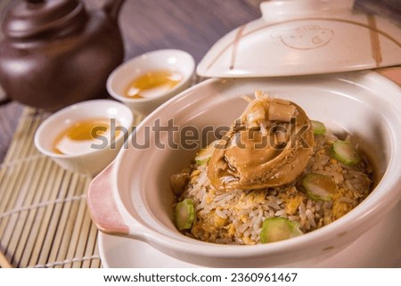 premium stewed chinese wok fried egg rice with whole abalone seafood vegetable in hot clay pot on wood table tea pot asian Chinese halal food restaurant banquet cuisine cafe menu