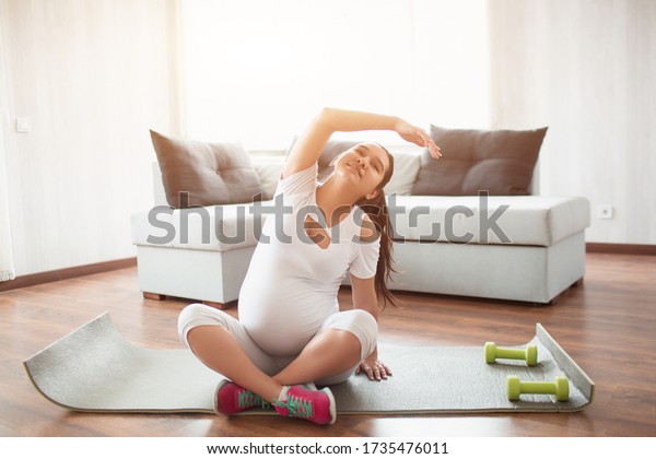 Pre-natal\
exercise. Pregnant woman exercising at\
home