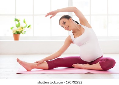 Pre-natal exercises. Beautiful pregnant woman exercising while sitting in lotus position 