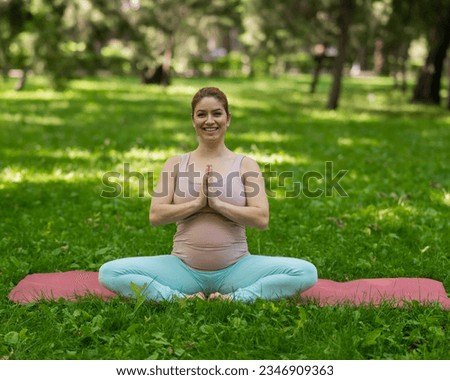 Prenatal yoga. Caucasian pregnant woman doing butterfly pose in the park.