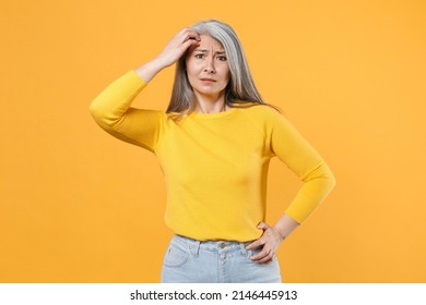 Preoccupied puzzled worried concerned perplexed gray-haired asian woman wearing casual clothes standing put hand on head looking camera isolated on bright yellow colour background, studio portrait - Shutterstock ID 2146445913