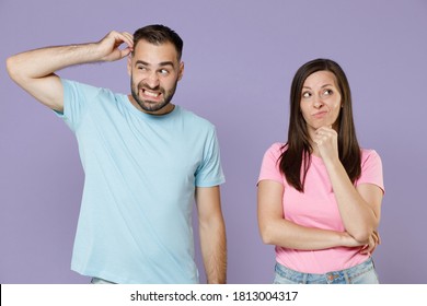Preoccupied puzzled young couple two friends man woman 20s in blue pink empty blank t-shirts put hand prop up on chin head looking aside isolated on pastel violet color background studio portrait - Shutterstock ID 1813004317