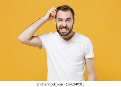 Preoccupied young bearded man 20s in white casual t-shirt posing isolated on yellow wall background studio portrait. People lifestyle concept. Mock up copy space. Put hand on head, looking aside - Shutterstock ID 1890249313