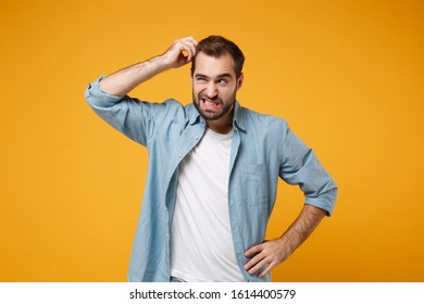 Preoccupied young bearded man in casual blue shirt posing isolated on yellow orange background studio portrait. People emotions lifestyle concept. Mock up copy space. Putting hand on head, looking up - Shutterstock ID 1614400579