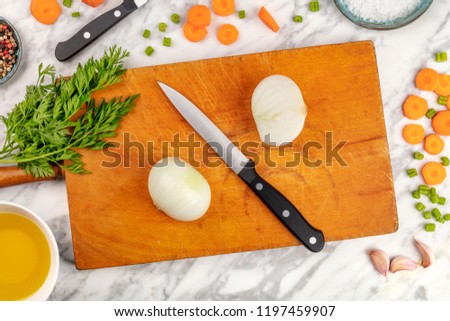 Prep time, or mise en place. An overhead photo of a professional chef's knive, shot from above on a cutting board, with chopped vegetables and spices, on a marble cooking surface with copy space