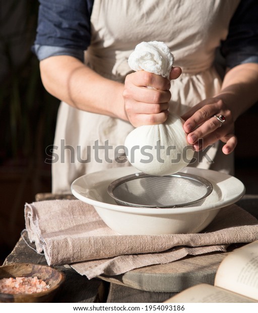 Preparation of almond milk - woman straining\
the milk through a\
cheesecloth