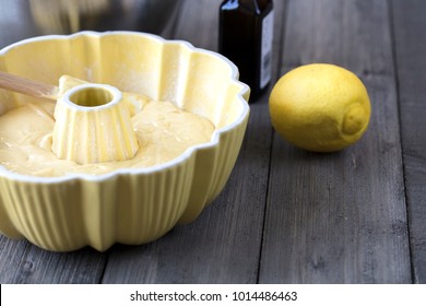 Preparation Of Batter For A Lemon Cake In A Yellow Bundt Pan With A Spatula On A Rustic Table Top