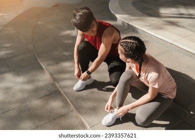 Preparation before jogging exercise. Together young Asian man and woman tying shoelace on her running shoes. Fitness and sport activity. Healthy exercise concept. - Powered by Shutterstock
