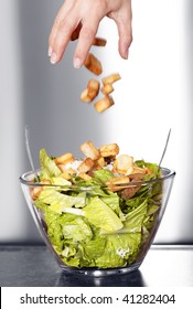 Preparation Of A Caesar Salad In A Glass Bowl. Movement Blur Of Crouton Falling In The Salad. Selective Black And White With Shallow Depth Of Field.