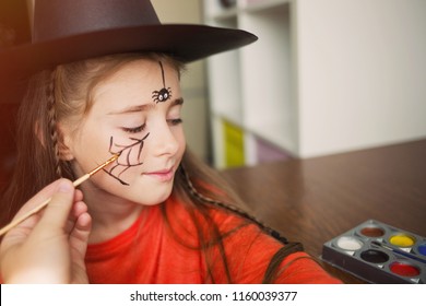preparation for the celebration Halloween  child in witch outfit doing face painting  cute spider  idea simple suit  diy