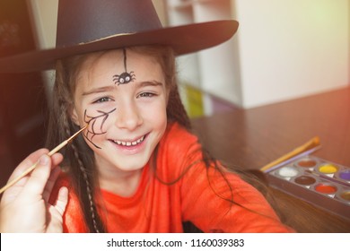 preparation for the celebration Halloween  child in witch outfit doing face painting  cute spider  idea simple suit  diy  toned
