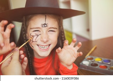 preparation for the celebration Halloween  child in witch outfit doing face painting  cute spider  idea simple suit  diy  toned