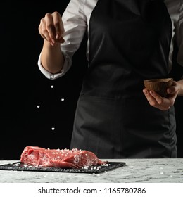 Preparation of the chef by steak cook.Preparation of fresh beef or pork. Horizontal photo with dark black background. - Shutterstock ID 1165780786