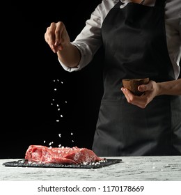 Preparation of the chef by steak cook.Preparation of fresh beef or pork. Horizontal photo with dark black background. - Shutterstock ID 1170178669