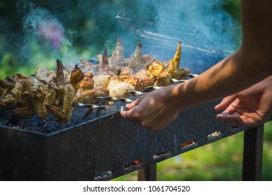 Preparation of chicken skewers on a brazier on skewers, on the right in the frame of the hand, skewers are turned over with chicken shish kebab