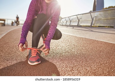 Preparation. Cropped Shot Of Active Mature Woman Wearing Sportswear Tying Her Shoelaces While Getting Ready For Running Outdoors On A Sunny Day