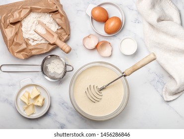 Preparation of dough for home pancakes for Breakfast. Ingredients on the table - wheat flour, eggs, butter, sugar, salt, milk. Selective focus