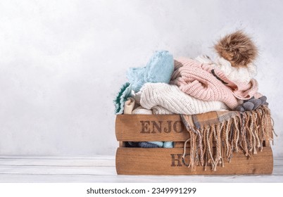 Preparation for fall and winter season, autumn warm cozy clothes, Stack of clean freshly laundered, neatly folded jackets, sweaters, blankets, hats, mittens in wooden box, taken from the mezzanine - Powered by Shutterstock