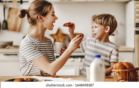 Preparation Of A Family Breakfast. Mother And Child Son Cut Bread And Eat Cookies With Milk In Morning
