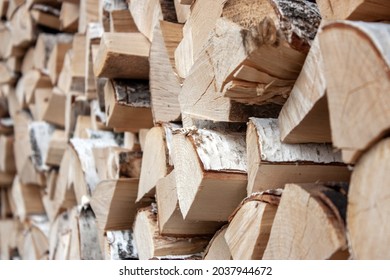 Preparation of firewood for the winter. View of the woodpile of firewood. Chopped firewood is randomly placed in a pile. The ends of chopped firewood close-up, side view.